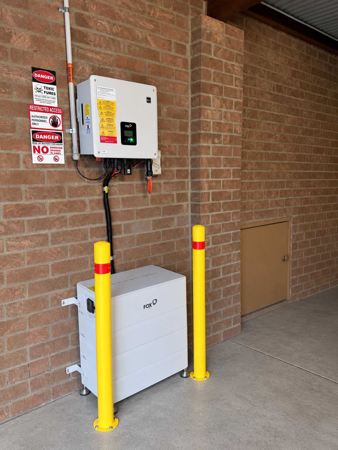 Fox ESS battery below a separate inverter, with yellow bollards and space above the battery for a planned upgrade.